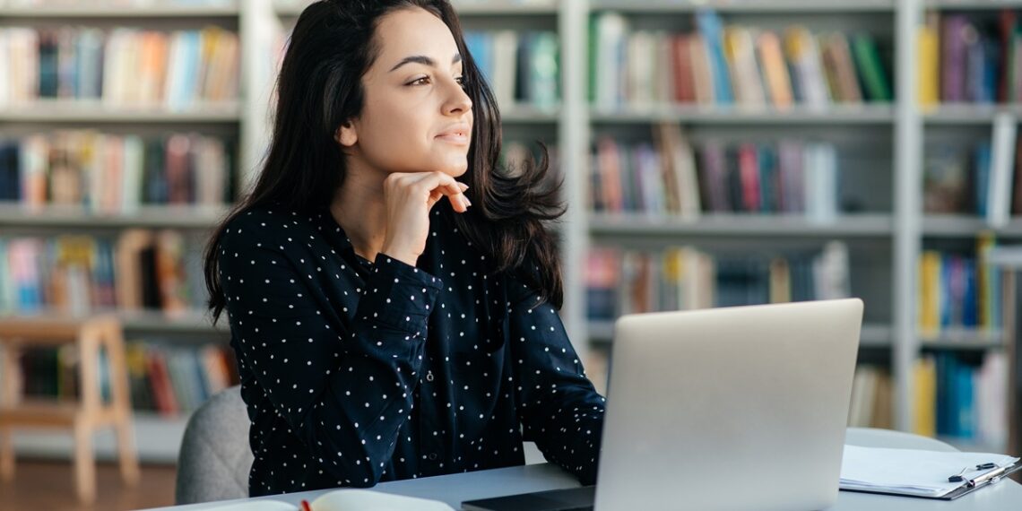 Étudiante assis derrière son portable qui prend une pause et qui réfléchit