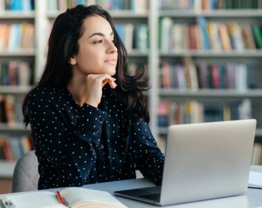 Étudiante assis derrière son portable qui prend une pause et qui réfléchit