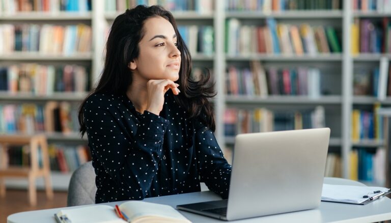 Étudiante assis derrière son portable qui prend une pause et qui réfléchit